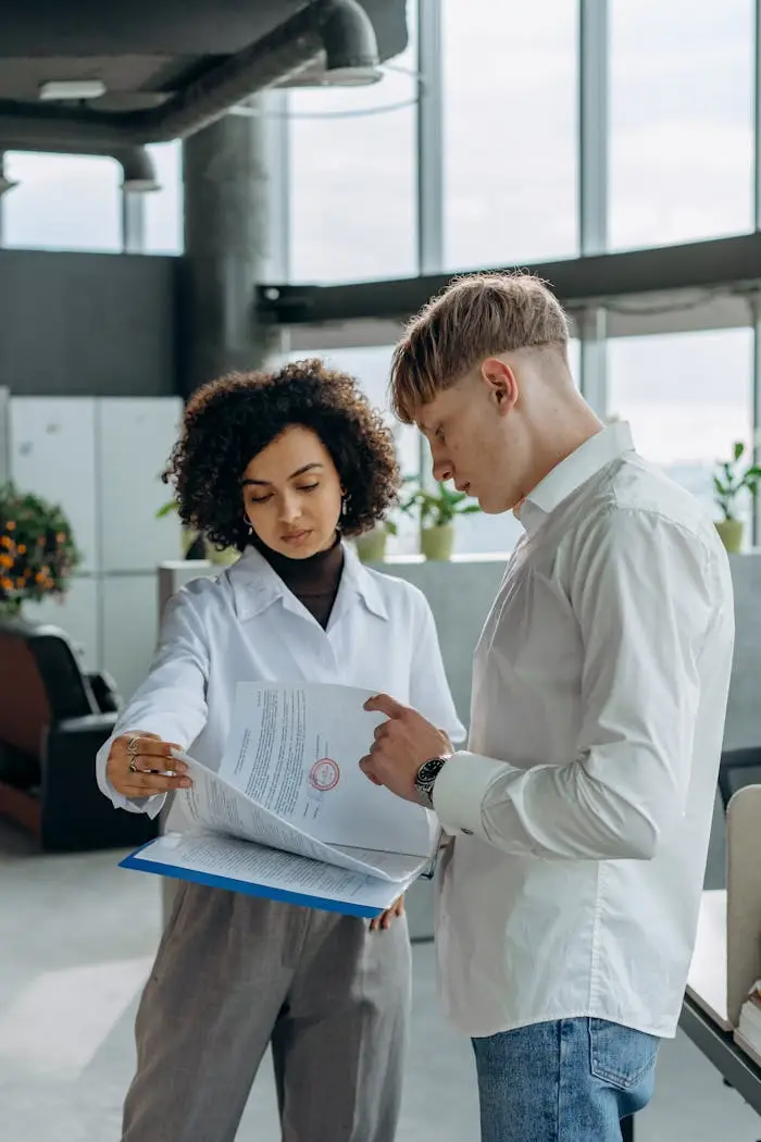 Two professionals discussing paperwork in a modern office setting.